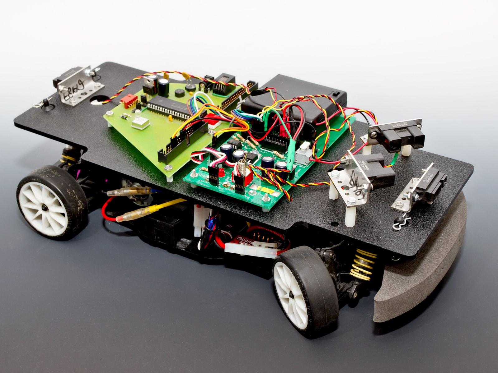 A four wheeled car with infrared sensors and exposed circuitry.